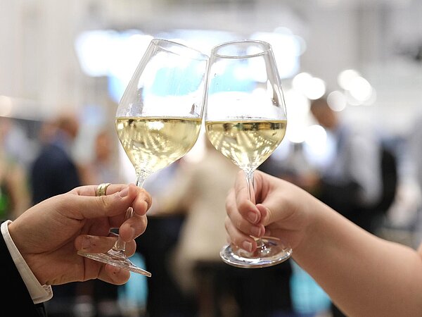 Close-up of two wine glasses being held in a man's and a woman's hand. They're clinking the glasses.