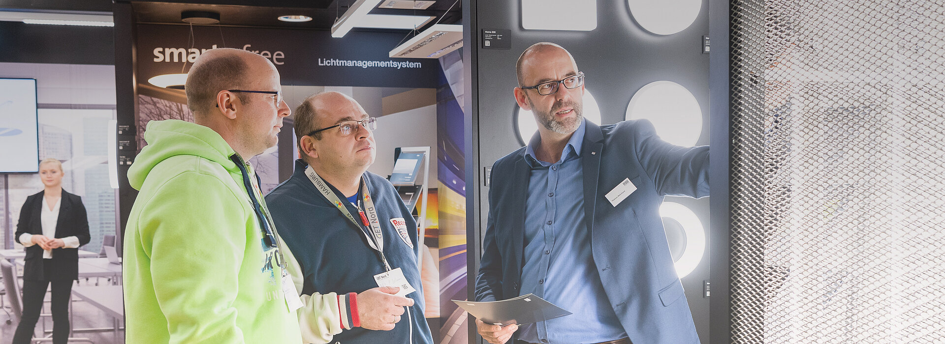 Three people are talking at the exhibition stand.