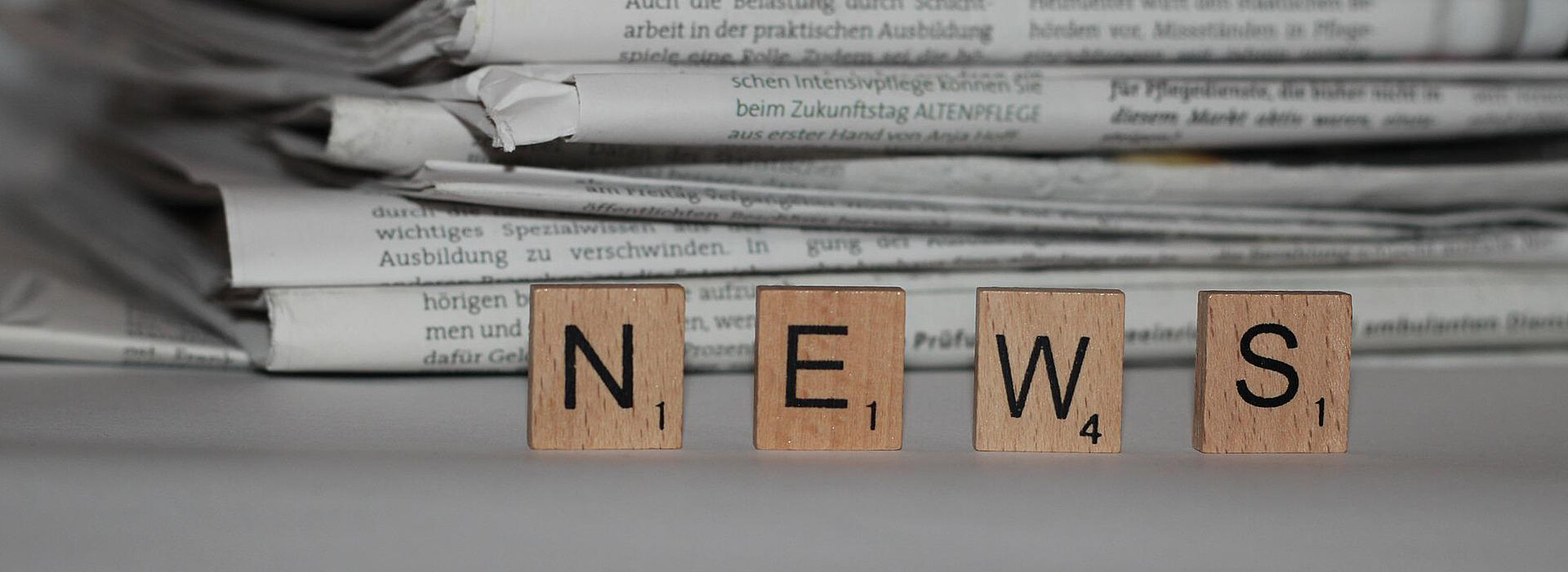 Scrabble Buchstaben NEWS vor Zeitungsstapel